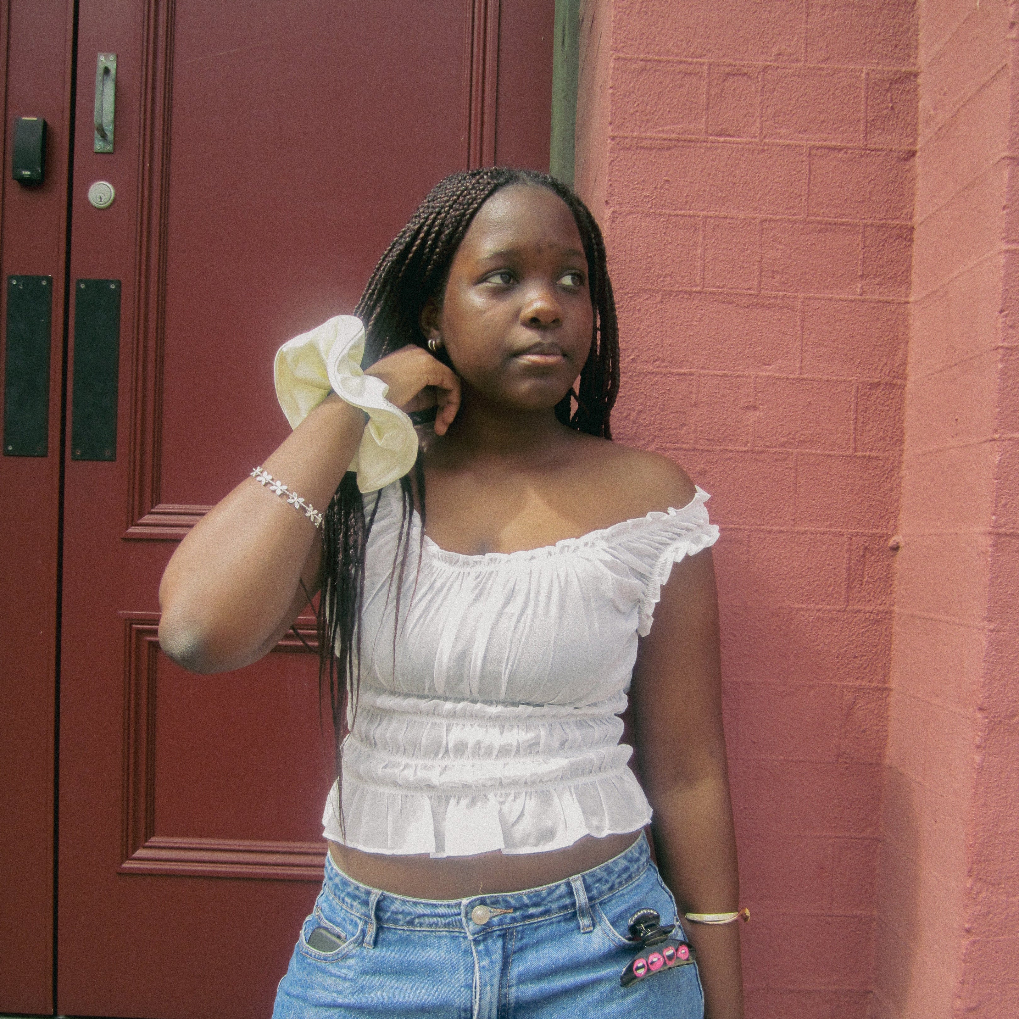 Luna Wave model in a white scrunchies standing against a red brick wall.