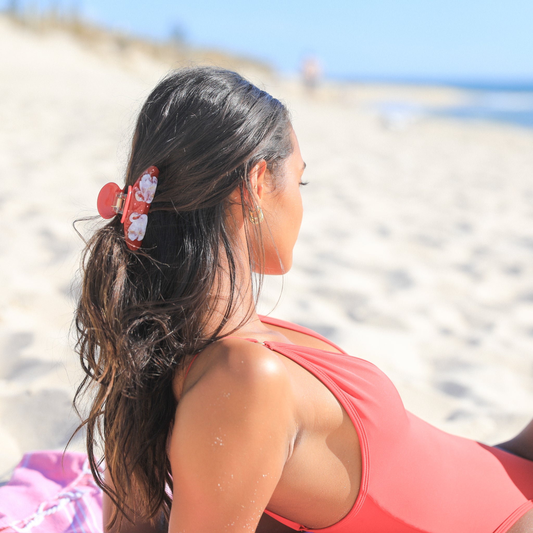 Woman with a Luna Wave red odette hair claw clip sitting on a beach