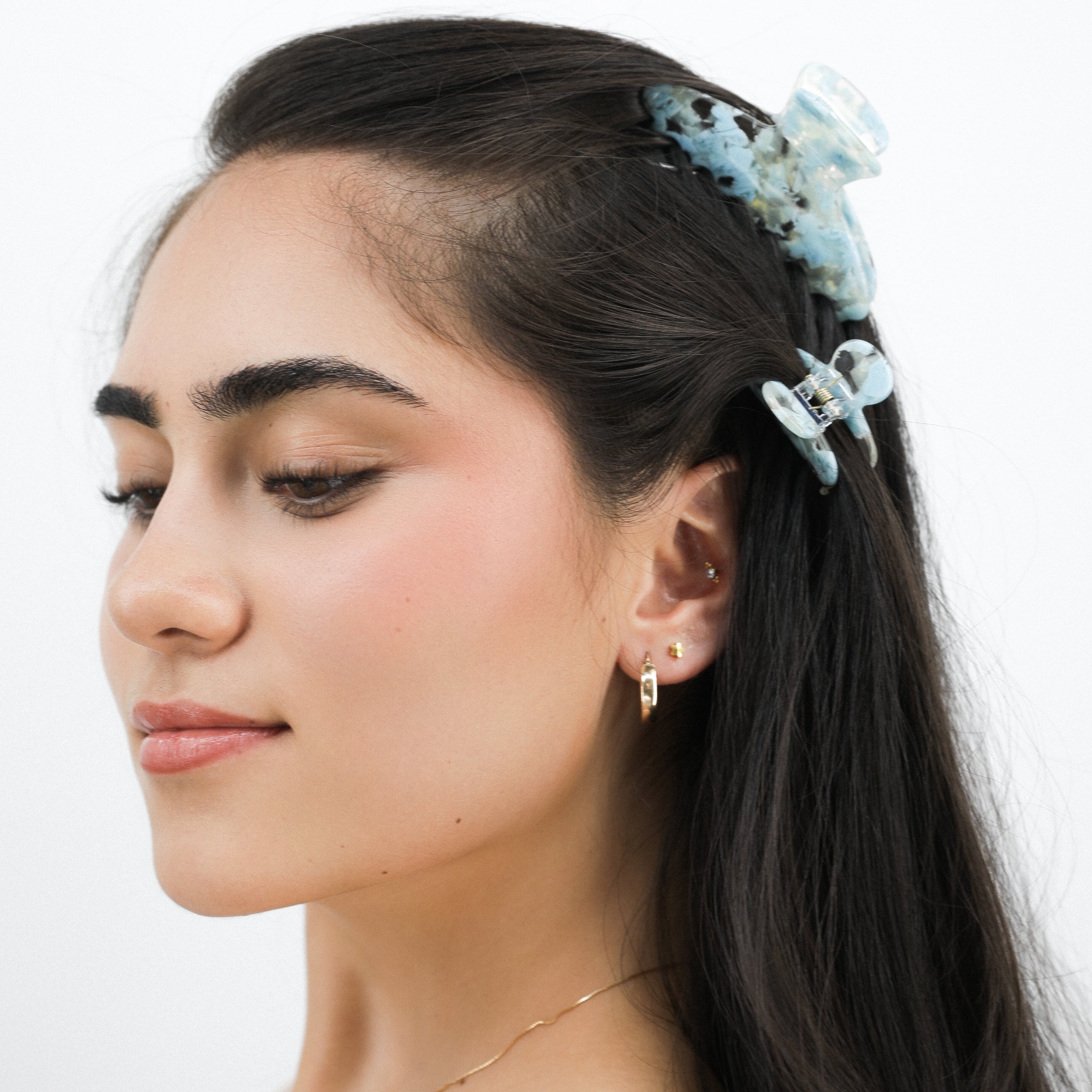 Woman with a Luna Wave blue mist floral hair claw clip on a white background
