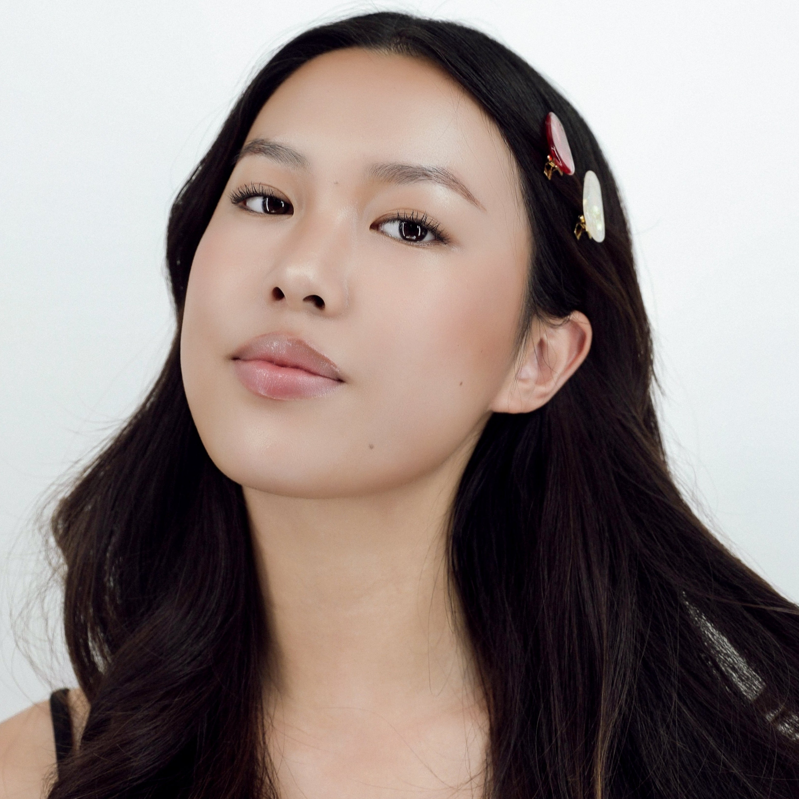 Woman with long dark hair wearing a Luna Wave red moon petite hair clips against a white background
