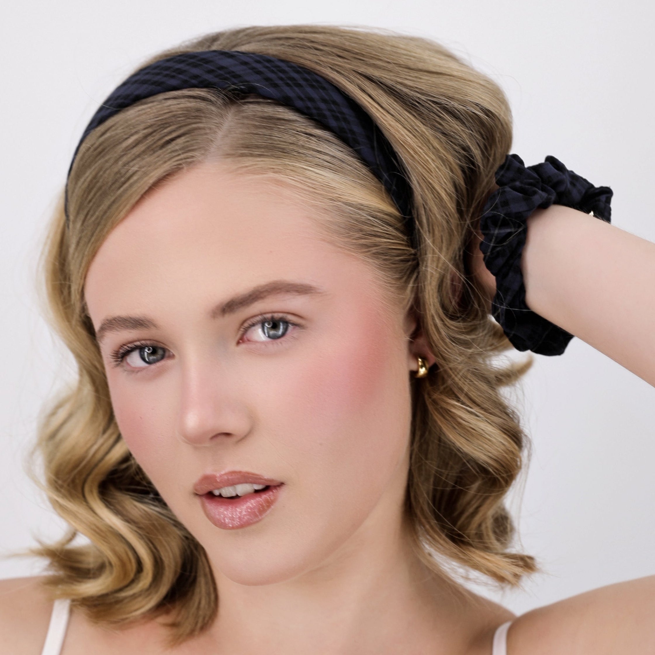 Woman with styled hair wearing a Luna Wave navy gingham headband against a plain background