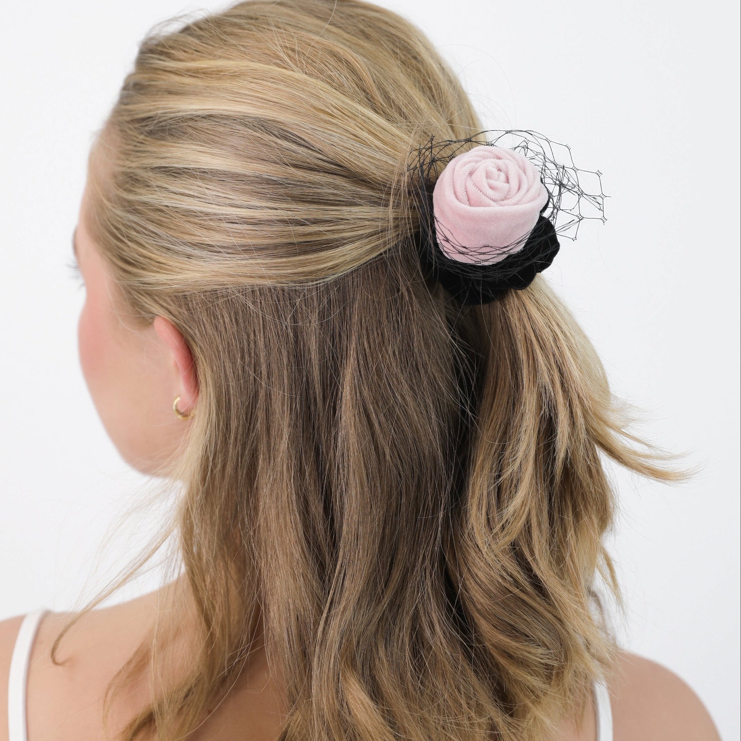 Person with a Luna Wave pink amelie rose scrunchie in their hair on a white background