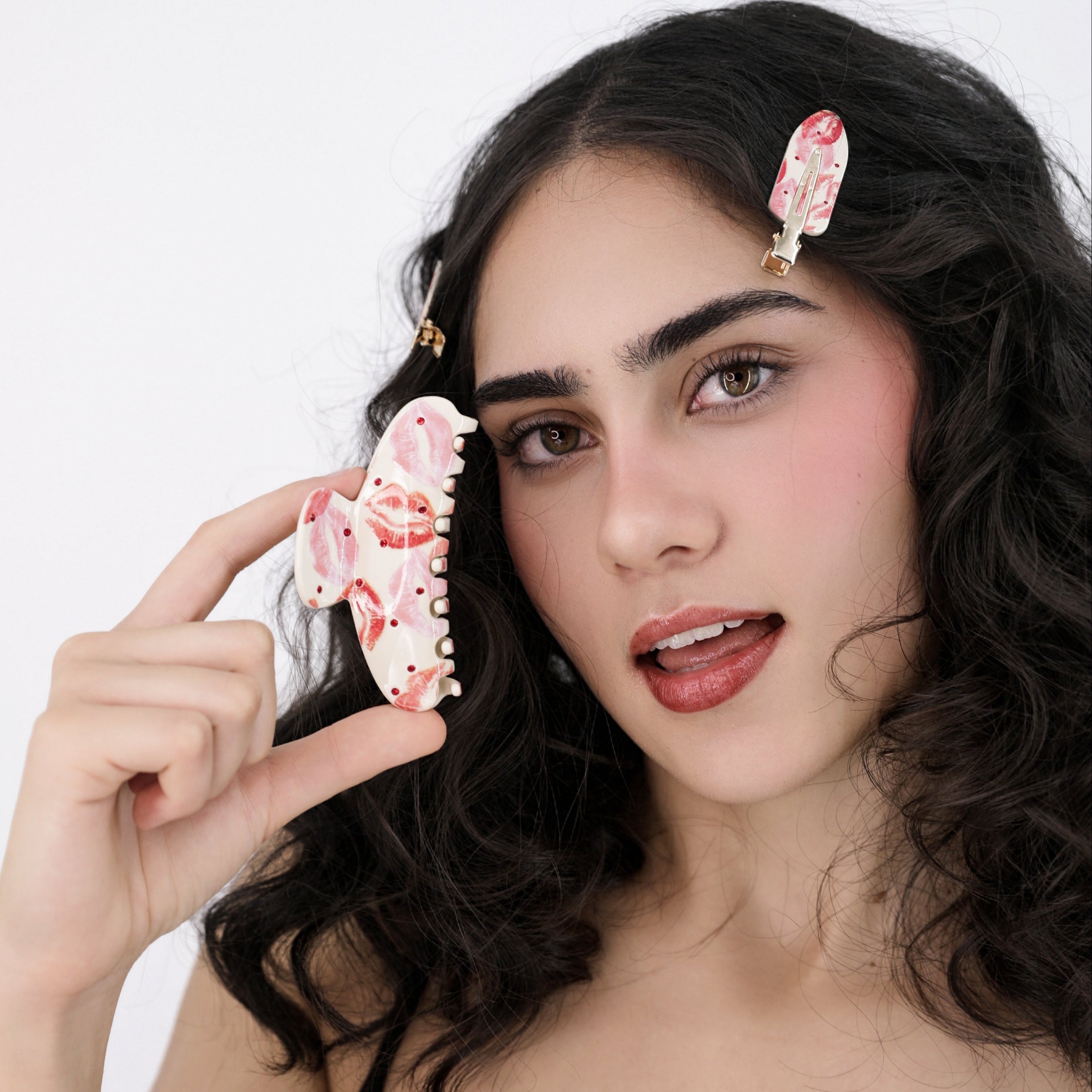 Woman holding a Luna Wave pink rosy hair claw clip against a white background
