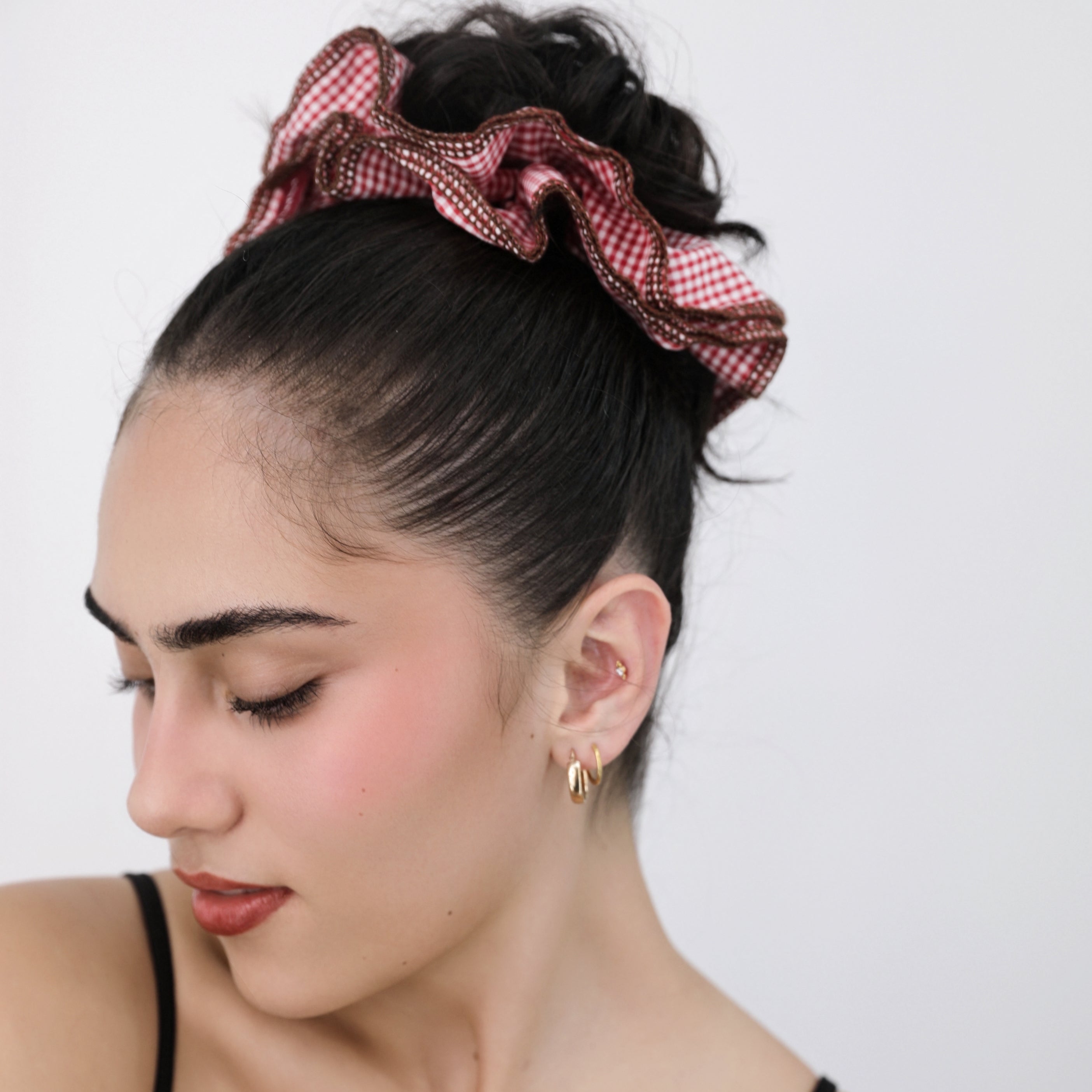 Woman with a Luna Wave red checkered scrunchie in her hair against a white background