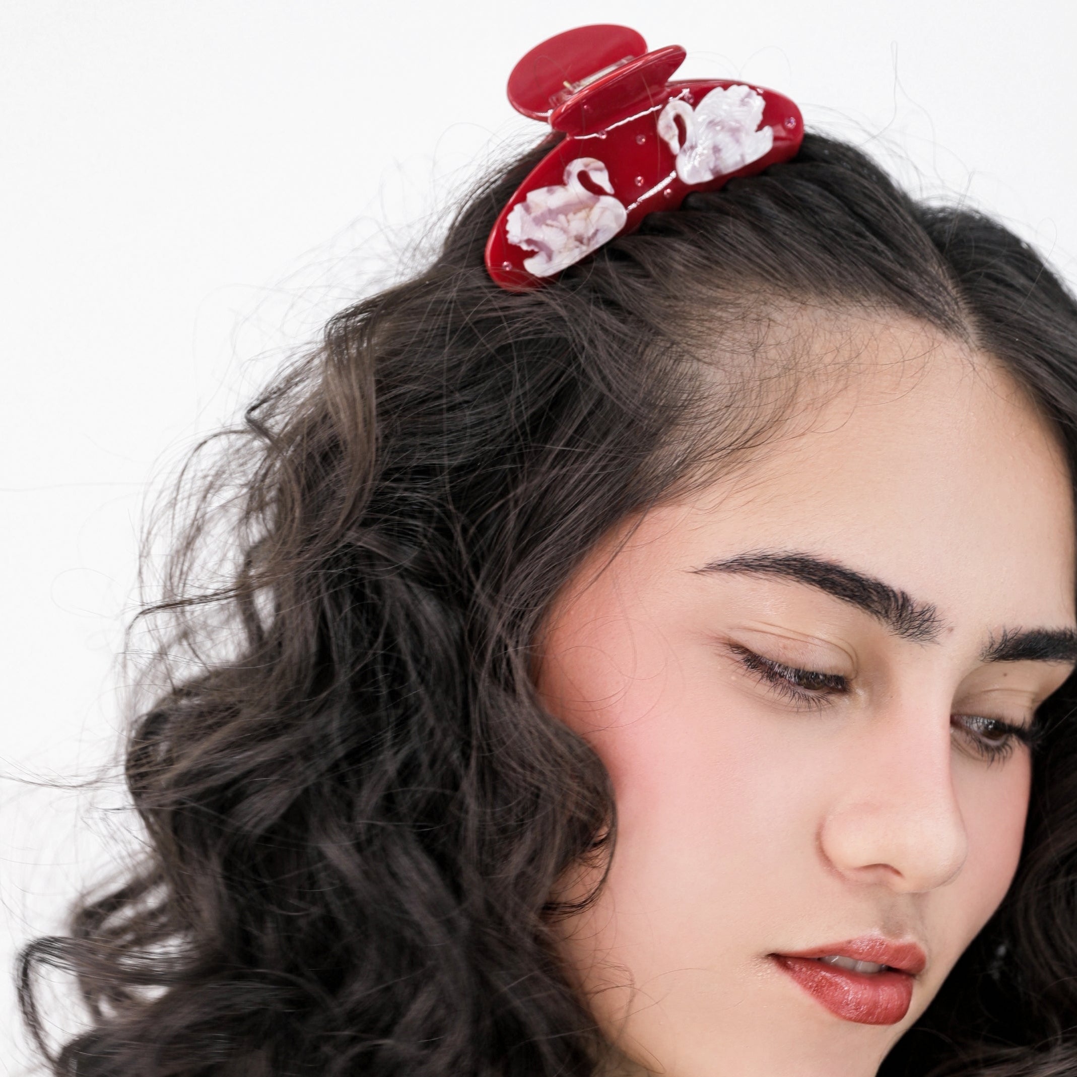 Woman with wavy hair wearing a Luna Wave red odette hair claw clip against a white background