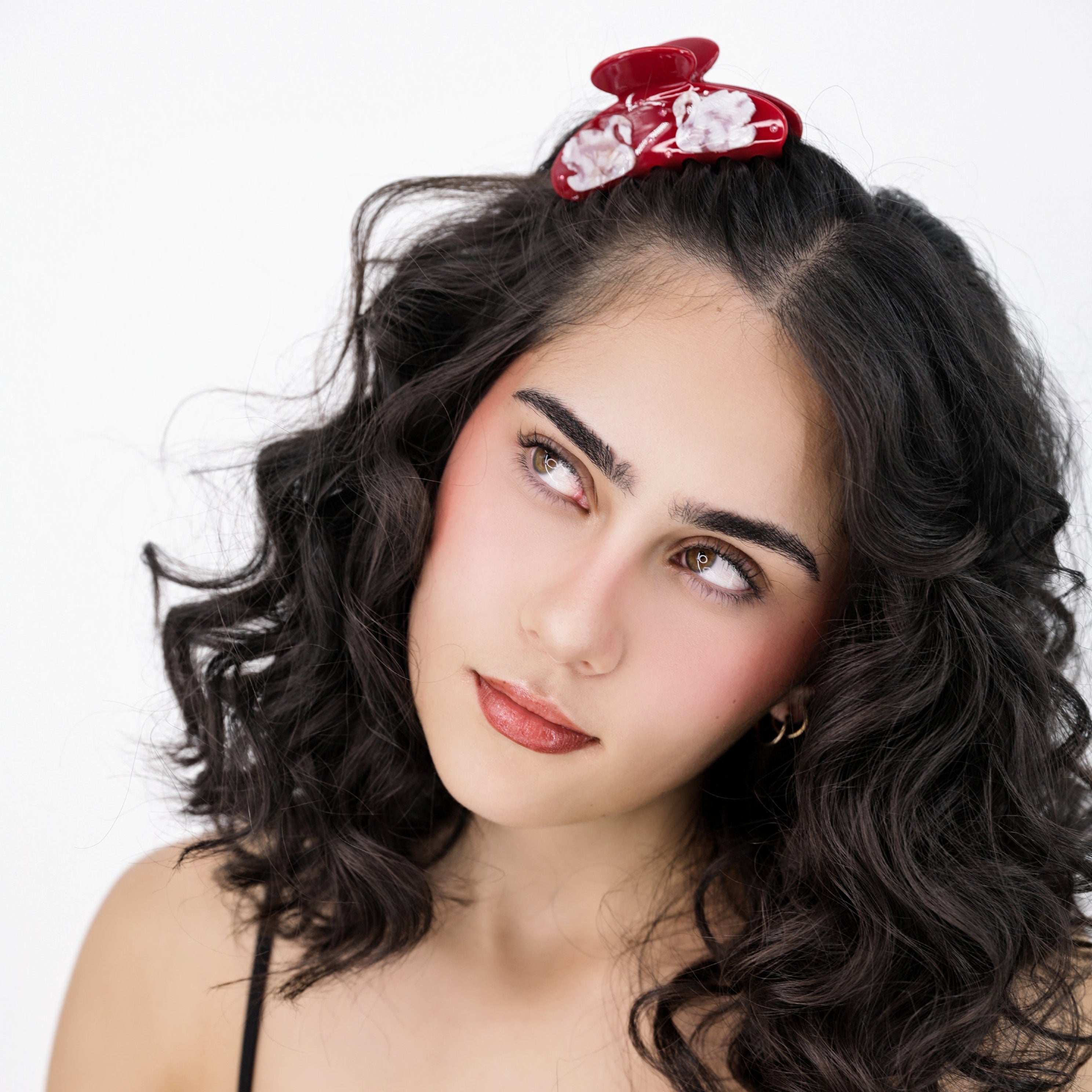 Woman with wavy hair and a Luna Wave red odette hair claw clip against a white background