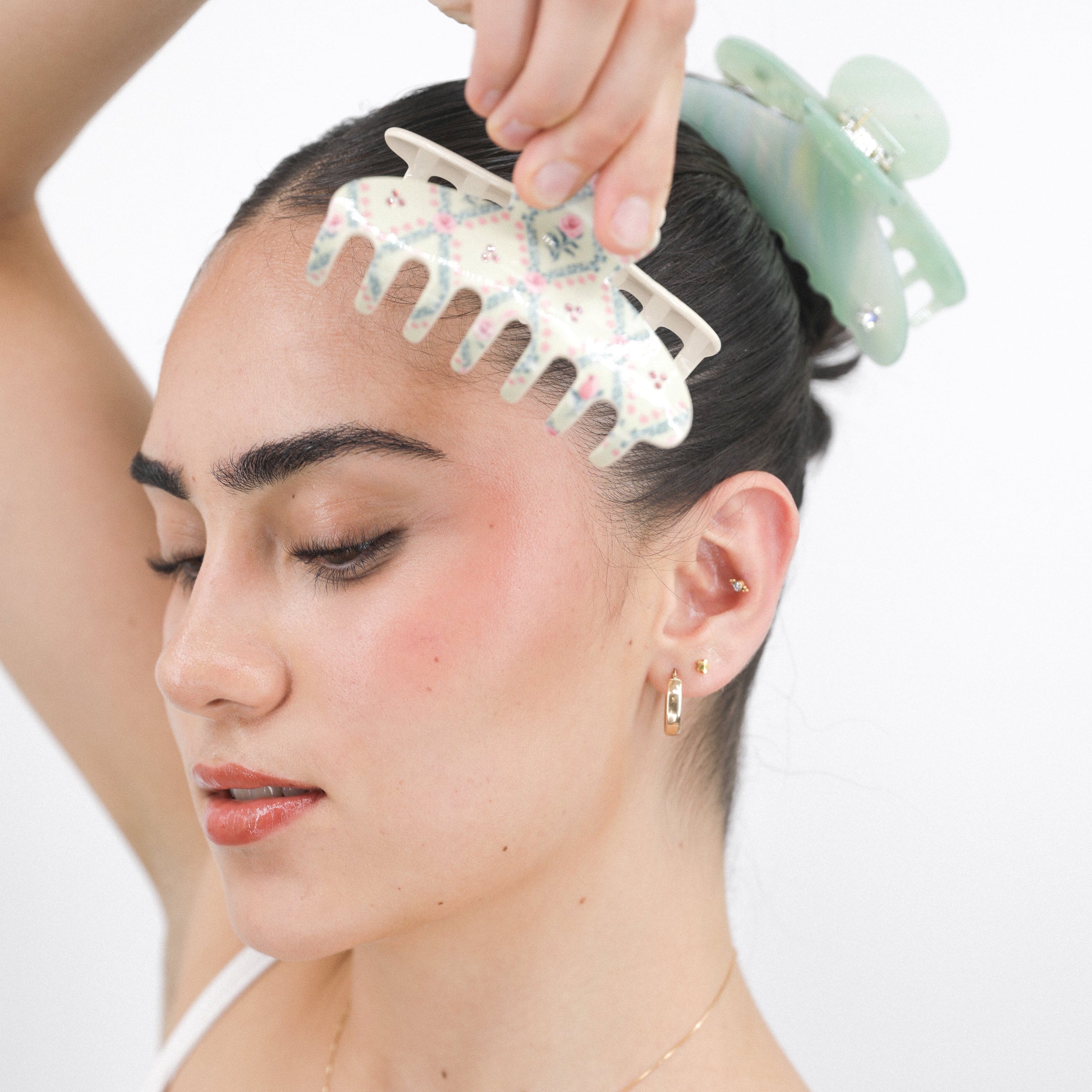 Woman using a Luna Wave white rose lattice hair claw clip on her head with a plain background