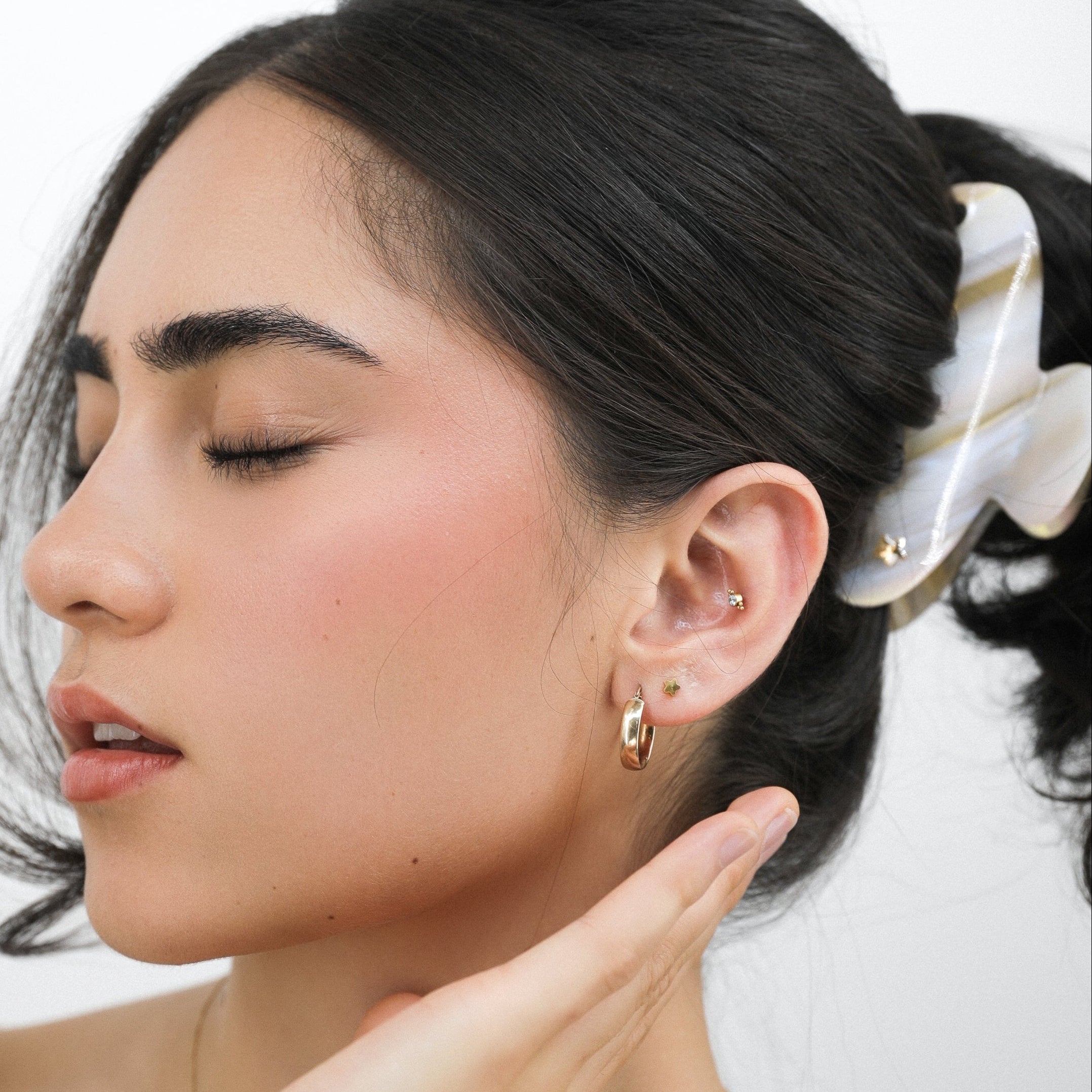Woman wearing Luna Wave orange starfish pearl hair claw clip with a white background