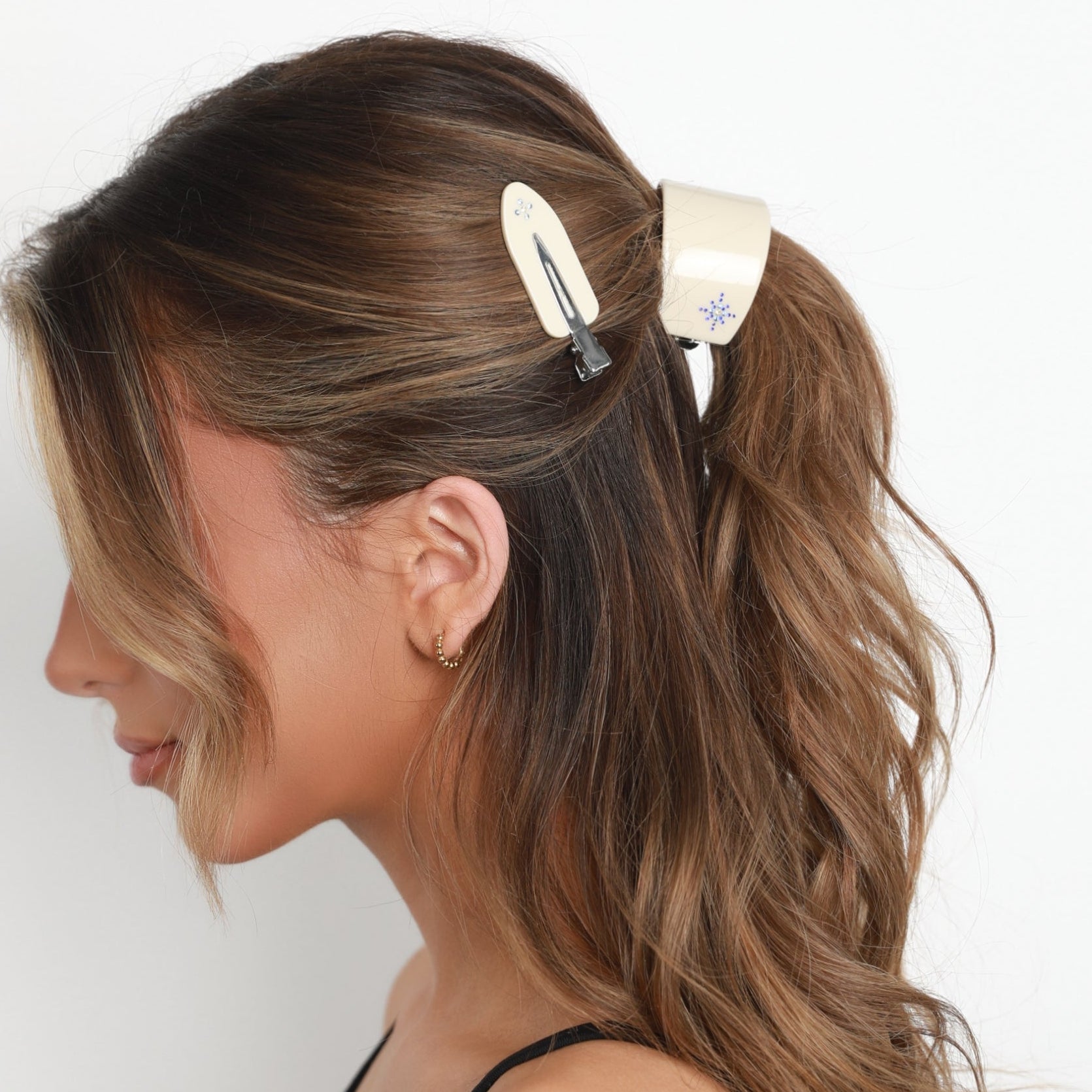 Woman with styled hair using a Luna Wave vanilla starlet barrette and hair clip on a plain background
