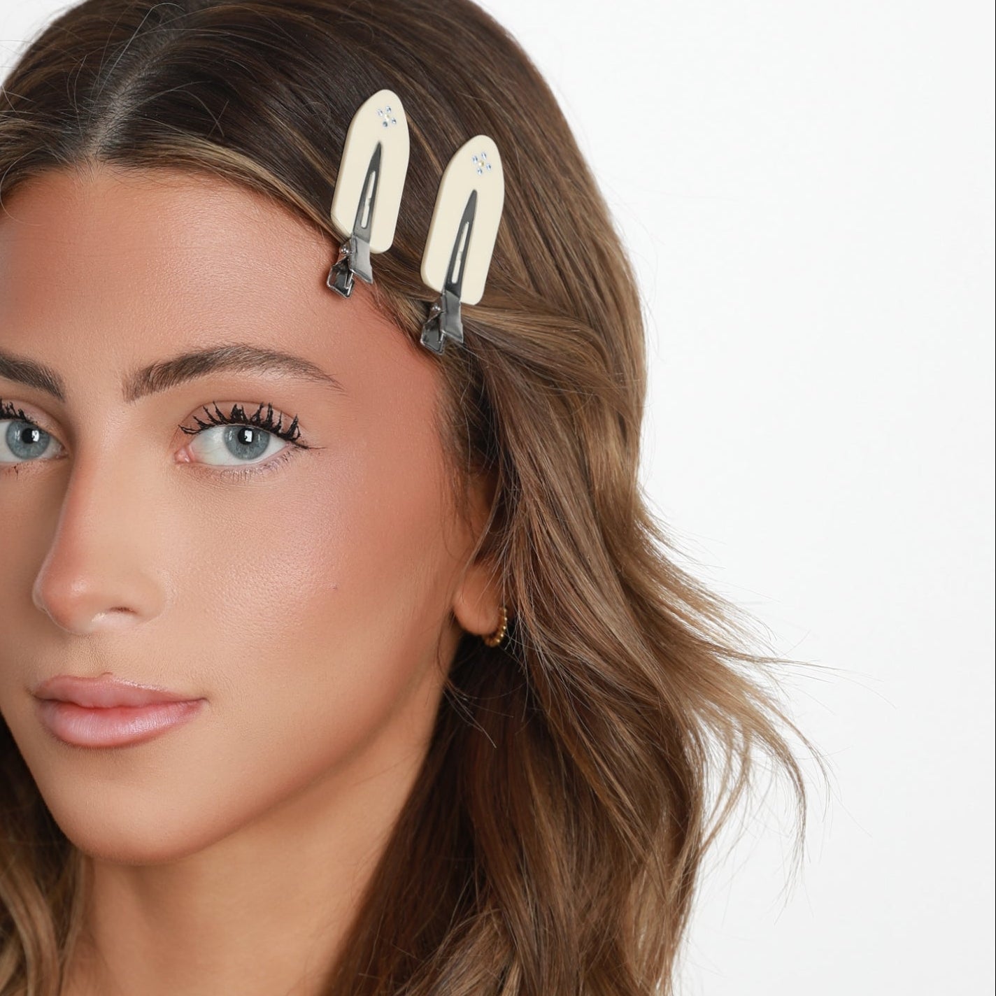Woman with wavy hair wearing two Luna Wave vanilla starlet hair clips against a white background