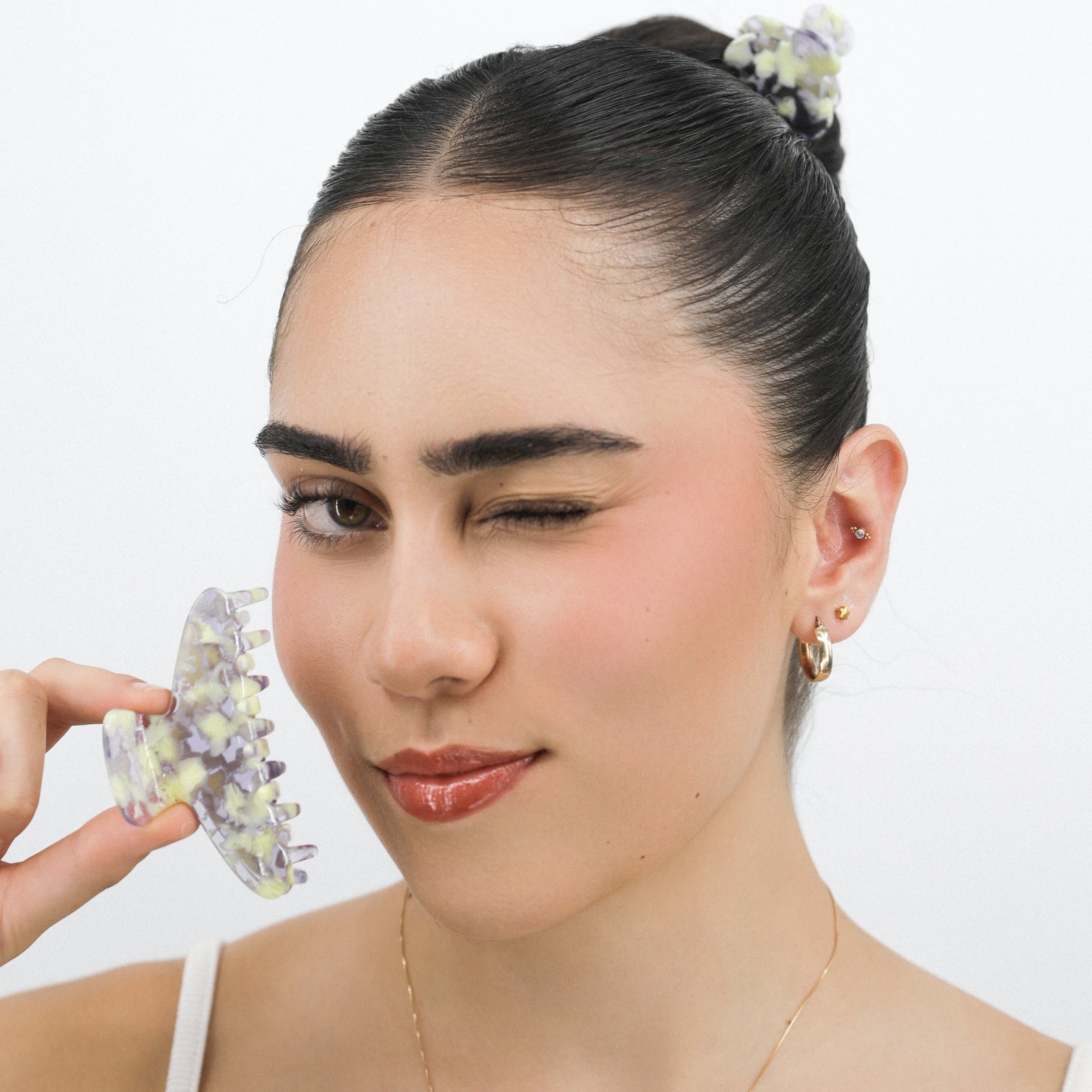 Lady holding a Luna Wave purple violet flora hair clip against a plain background
