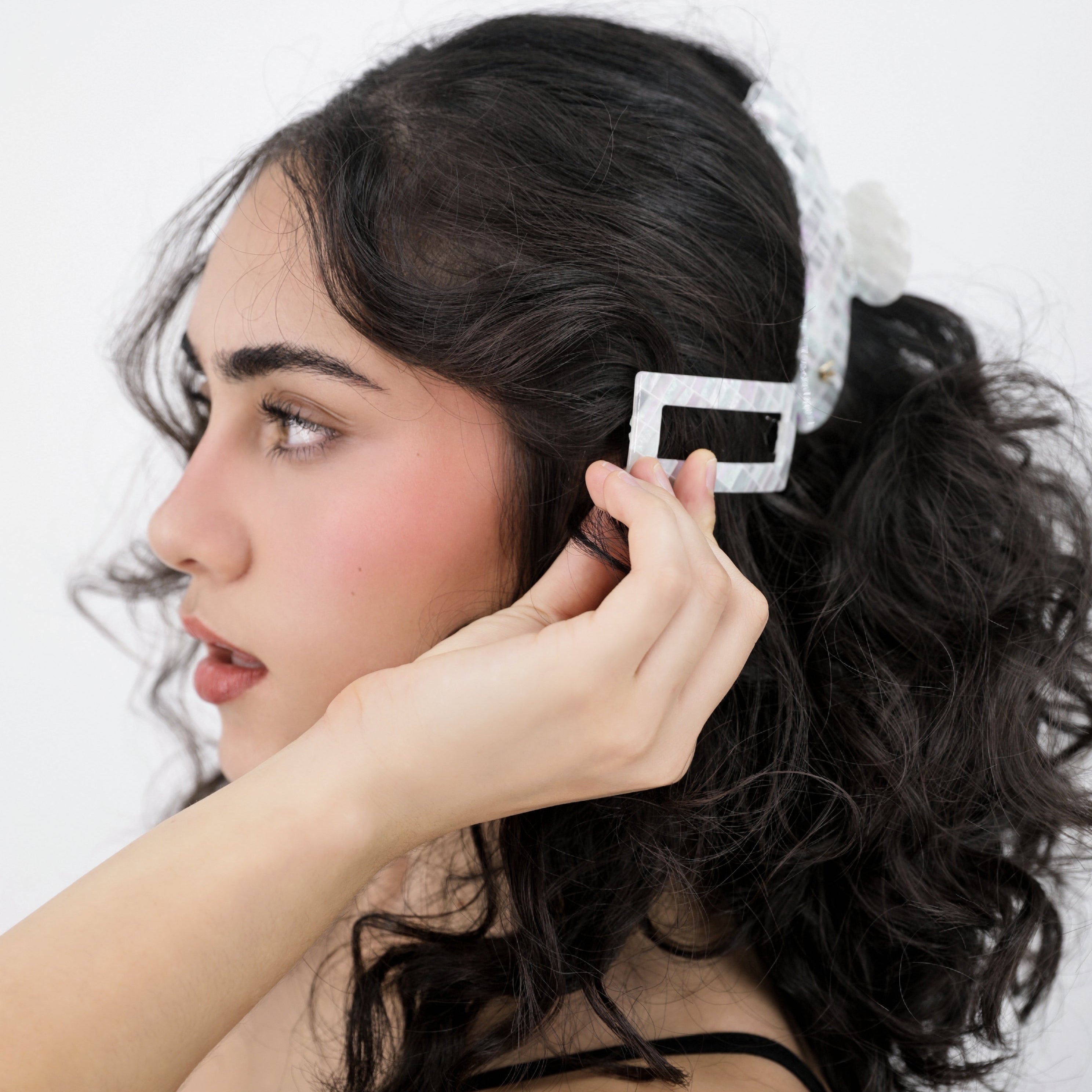 Woman adjusting a Luna Wave white opal earth hair barrette on a plain background