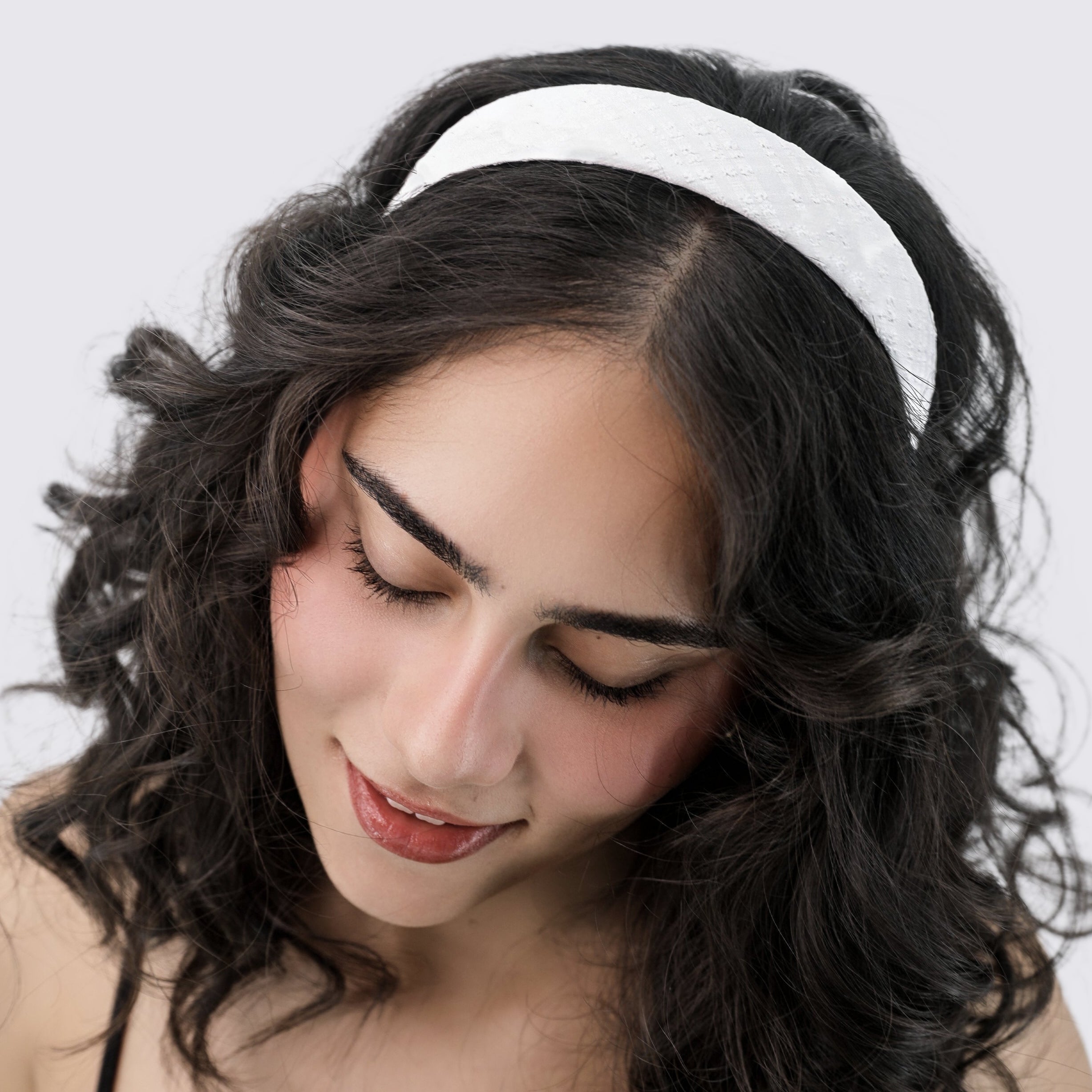 Woman wearing a Luna Wave white milk headband against a light gray background